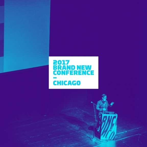 Speaker at podium on purple-lit stage with 2017 Brand New Conference Chicago screen