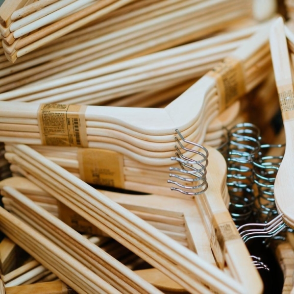 Close-up pile of light wooden clothes hangers with metal hooks