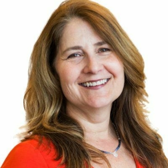 Smiling woman with long brown hair wearing a red top on a white background.
