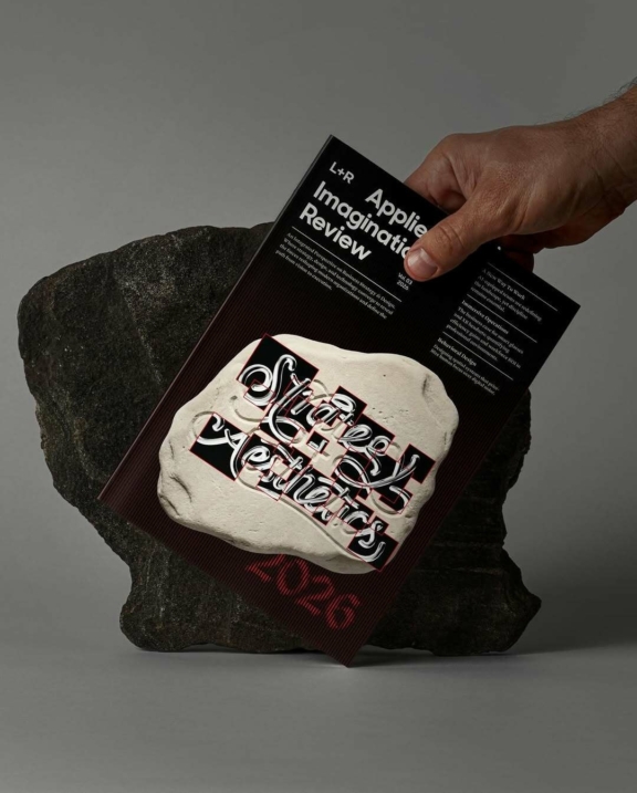 Hand placing a branded black card on a patterned tote bag beside a rock